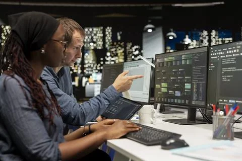 Manager and intern coding on PC in startup office, refining machine learning 写真素材