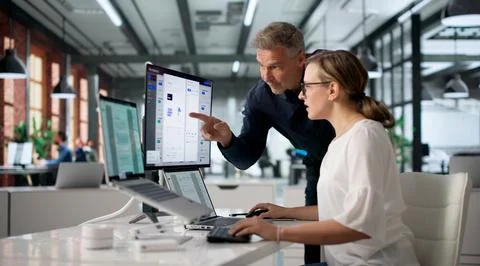 Manager And Team Discuss Digital Document System Using Laptop And Desktop. Stock Photos