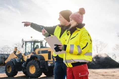 Manager and worker in biomass compost works engaged in discussion Foto stock