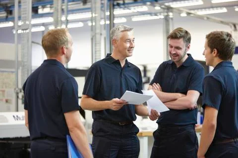 Manager and workers discussing paperwork in engineering factory Stock Photos