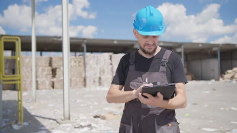 Manager with blue hard hat do calculations on tablet at paper recycling Video stock 248034412