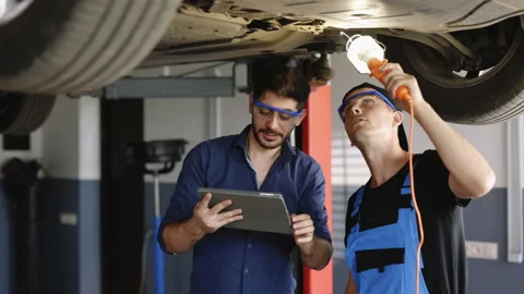 Manager Checks Data on a Tablet Computer and Explains the Breakdown to Mechanic Stock Footage 203718838