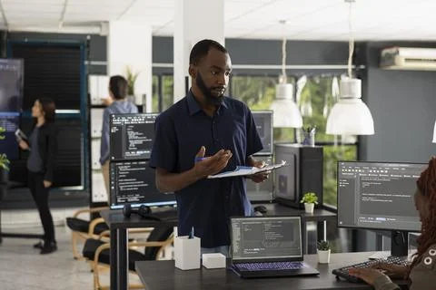 Manager checks progress with employee at computer during coding meeting Stock-Fotos