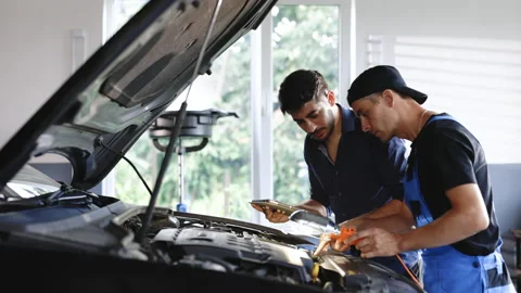 Manager checks tasts on tablet computer and explains an Engine breakdown to an Stock Footage 203479347