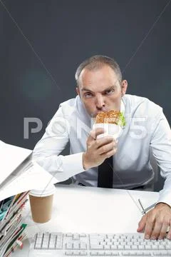 Manager chewing sandwich while working Stock Photos