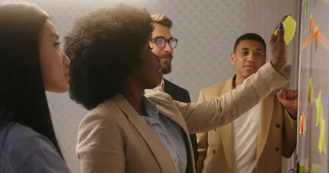 Manager with colleagues puts sticky notes on whiteboard Video stock 195378479