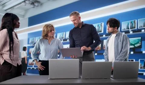 Manager Comparing Laptops With Workers At Electronics Store, Assessing Qualit Stock Photos