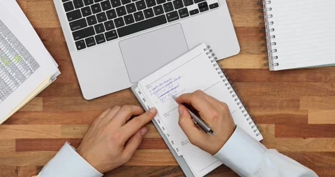 Manager crosses done tasks in plan list comparing at laptop Stock Footage 264754427