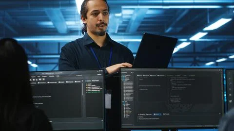 Manager in data center doing annual system review, checking parameters on laptop Stockfoto's