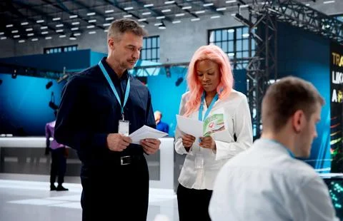 Manager Demonstrates AI Software To Diverse Team During Busy Trade Expo Event Stock Photos