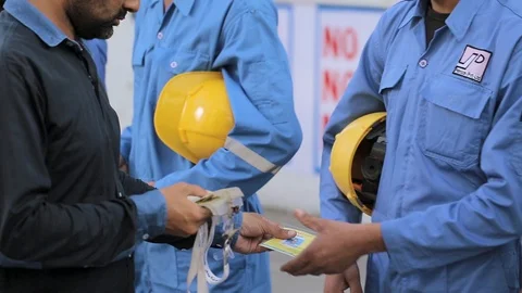 Manager distributes entry cards to factory workers carrying yellow safety helmet Vídeo Stock 91583542