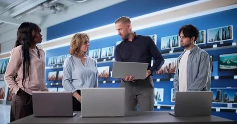 Manager Doing Laptop Comparison To Workers At Electronics Store, Showing Buil Stock Photos