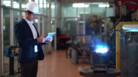 Manager engineer using digital tablet control  Welding robot arms machine in Stock Footage 154484937