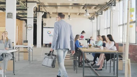 The manager enters the creative office space, welcomes colleagues and sits down Stock Footage 109417249