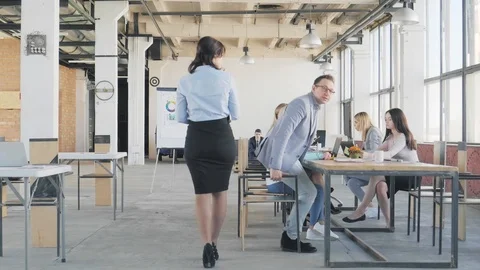 The manager enters the loft-style office space and greets the colleagues who sit Stock Footage 109503196