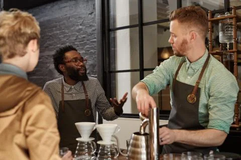 Manager explaining something to a staff member in coffee shop Stock Photos