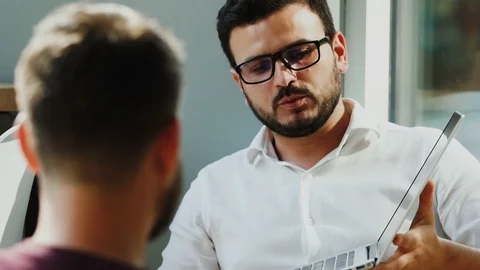 Manager in formal shirt showing computer screen to employee at interview in cafe Stock Footage 112991733
