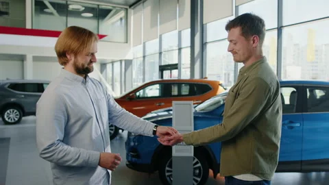The manager gives the man the keys to the bought car.Background car dealership Stock Footage 203768362