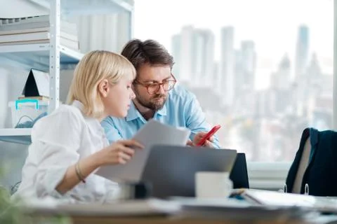 Manager giving feedback to young intern. Looking at smartphone Stock Photos