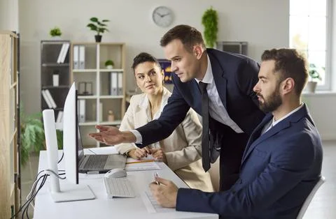 Manager guiding team at computer, office collaboration and analytics focus Stock Photos
