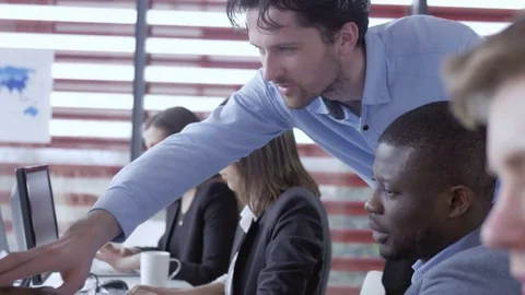 Manager helping to a new employee to do a task at the modern office Stock Footage 73934704