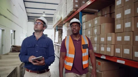 Manager inspecting parcels holding digital tablet while worker shows order of Stock Footage 140577777