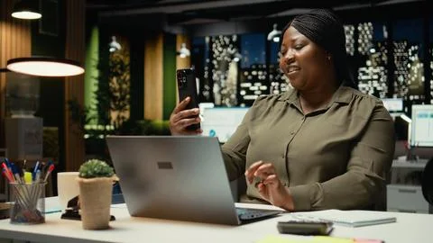 Manager joining remote webinar from office using her smartphone app Stock Photos