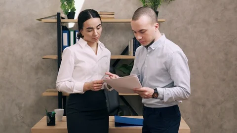 Manager looks at documents from junior employee in office Stock Footage 104903363