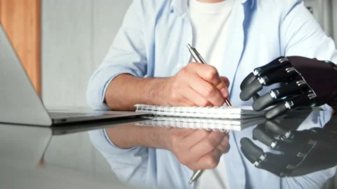 Manager man with bio hand prothesis makes notes in notebook Stockbeeldmateriaal 157347708