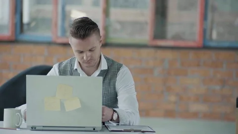 Manager man is sitting in the office at the workplace with a laptop and is Stock Footage 124269366