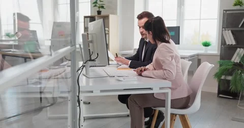 Manager mentoring coworker at computer in modern office, discussing project data Stock Footage 325778337