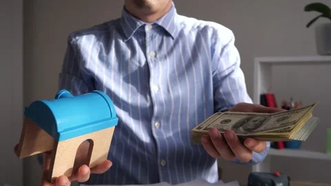 Manager in office holding house model and money. Stock Footage 306780650