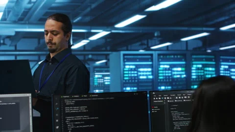 Manager overseeing server room, running code on laptop Stock Footage 275998931
