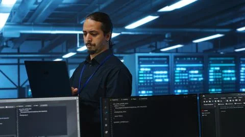 Manager overseeing server room, running code on laptop Stockfoto's