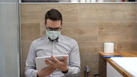 Manager in pandemic time. Remote work at home. Employee man in toilet use tablet Stock Footage 131463897