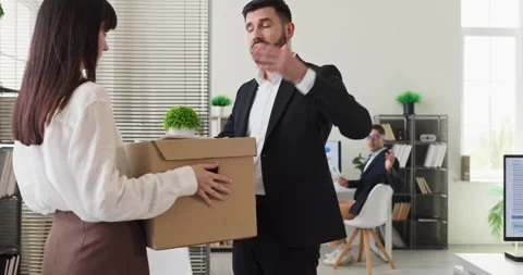 Manager pointing exit as employee carries box after dismissal in modern office Stock Footage 341470786
