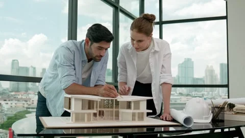 Manager pointing while cooperative coworker inspect house model. Tracery Stock Footage 262291966