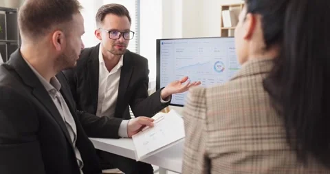 Manager presenting analytics to colleagues with charts on computer in office Stock Footage 342009702