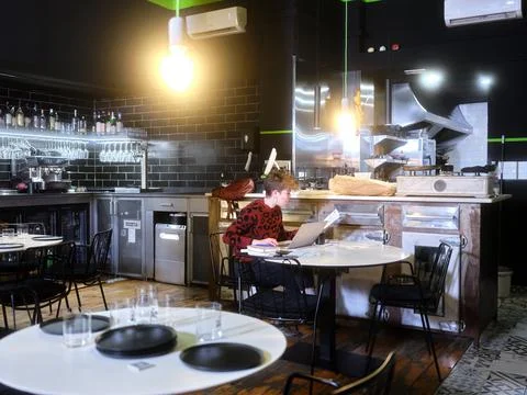 Manager of a restaurant working inside the establishment seated inside Stock Photos
