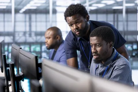 Manager in server hub overseeing workers using computer Stock Photos