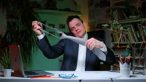 Manager sits at a table in the office, ties tie around his neck before a meeting Video stock 128028465