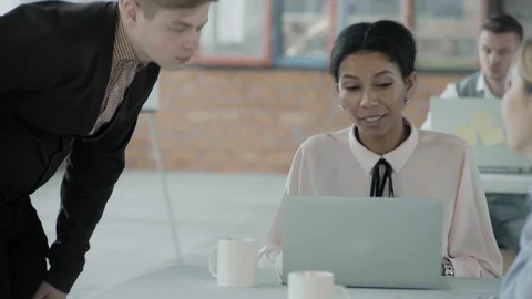 The manager stands near the desktop and communicates with a female employee of Stock Footage 124270077