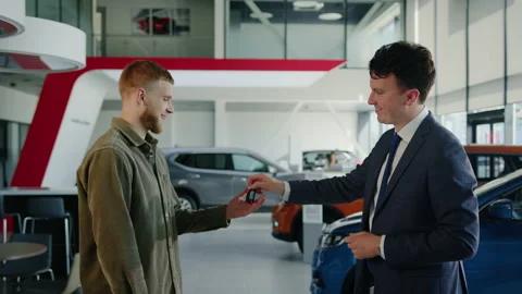 The manager in a suit and tie hands the keys to the car buyer Stock Footage 203768272