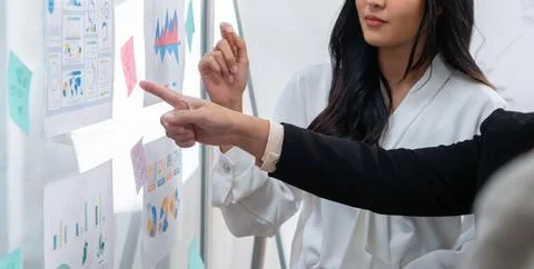 Manager with suit pointing at whiteboard to his female colleague Intellectual. Foto stock
