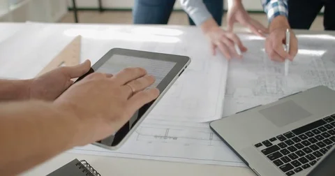 The manager with the tablet helps employees in the work on the drawings Stock Footage 82273316