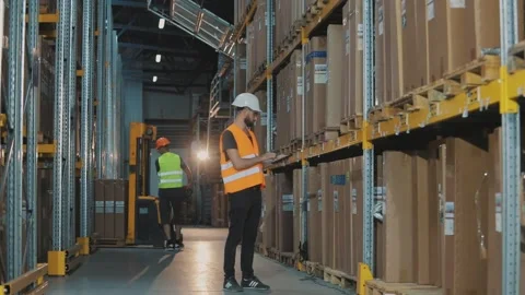 A manager with a tablet in a warehouse checks the goods. Warehouse manager of a Stock Footage 292873840