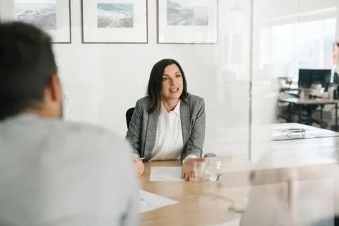 Manager talking with employees at her office desk Stock Photos