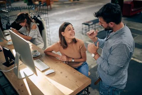 Manager talking to female worker sitting in front of desktop computer. Stock Photos