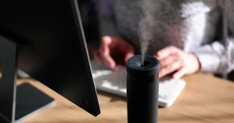 Manager types sitting at table with aroma diffuser humidifier Stock Footage 242192597