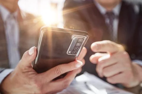 Manager uses smartphone while sitting at table with colleague Stock Photos